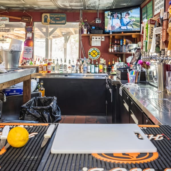 A rustic bar with bottles, beer taps, garnishes, and a TV playing golf.